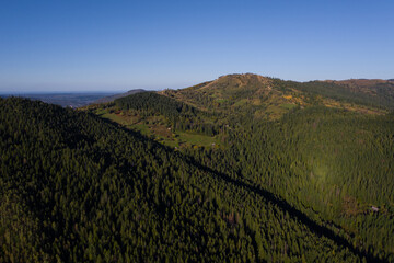 Summer mountain landscape, beautiful scenery of Carpathian mountains in Western Ukraine. High mountain peaks, blue sky, green forests and a small village at the foot of the hill.