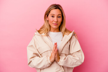 Young mixed race woman isolated on pink background praying, showing devotion, religious person looking for divine inspiration.
