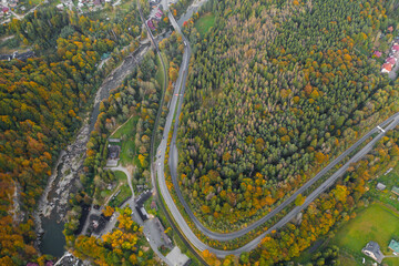 Obraz premium Aerial top view of a beautiful mountain village Yaremche in Carpathian mountains, Western Ukraine. Mountain river, houses and hotels, autumn forest and a long road. Beautiful landscapes and nature.