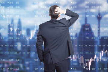 World trade market crisis concept with businessman grabs his head in looking at digital scoreboard with market quotes and falling graphs