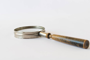An old magnifying glass on a light background. The concept of information search. Selective focus.