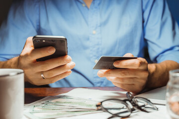 Stressed young businessman calculating monthly Family expenses, taxes, checking bank account balance credit card payment, Income at home night. Cropped shot male hands paying bill online on smartphone