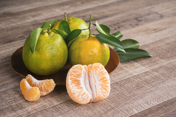 Fresh green tangerine mandarin orange on dark wooden table background.