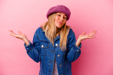 Young mixed race woman isolated on pink background doubting and shrugging shoulders in questioning...
