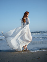 Fototapeta na wymiar Portrait of a woman in a dress by the ocean on the beach, in full growth