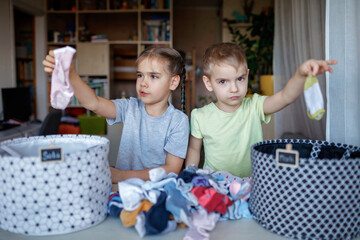 Household chores for children. Kids cleaning their room, sorting dry socks and arranging them into personal baskets with fun, they turn cleaning into the game. Everyday routine, lifestyle
