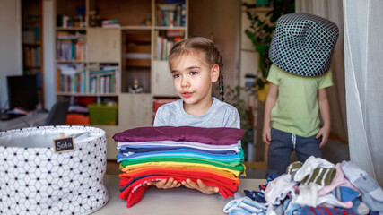 Household chores for children. Kids cleaning their room, sorting dry socks and arranging them into personal baskets with fun, they turn cleaning into the game. Everyday routine, lifestyle