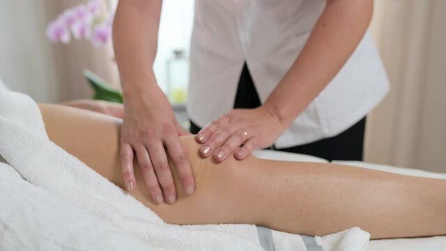 Unrecognizable beautician doing legs draining massages.