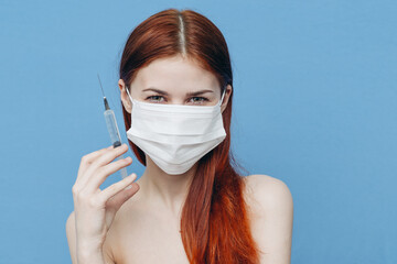 woman on a blue background in a medical mask and syringes in hand botox injection beauty care