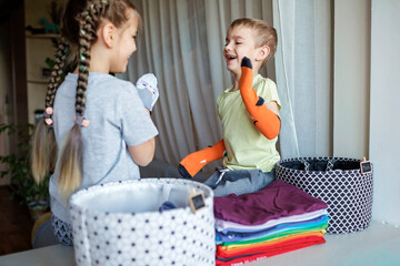 Household chores for children. Kids cleaning their room, sorting dry socks and arranging them into personal baskets with fun, they turn cleaning into the game. Everyday routine, lifestyle