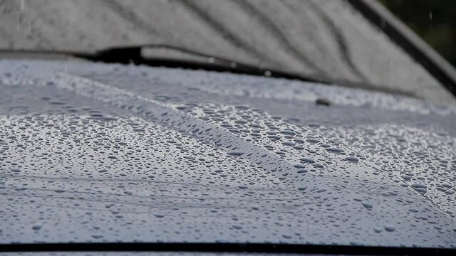 rain falling on the hood of a blue car, wet car, rainy and cold weather