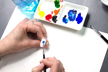 Nail art design on nail tips with a fine brush of watercolor paint. The manicure master draws,...