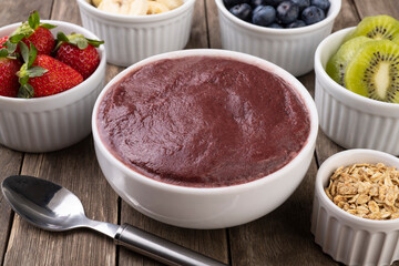 Brazilian typical acai bowl with fruits and muesli over wooden background