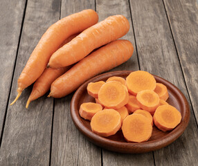 Carrots and slices on a plate over wooden table