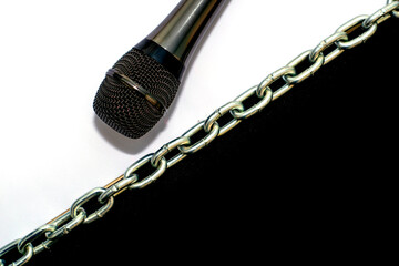 on a black-and-white background, blocked by an iron chain, lies the microphone concept of freedom of speech
