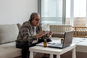 Photo of a senior male patient discuss about drug medicine with doctor in online using laptop computer. Elderly man having an online virtual consultation with his doctor while staying isolated at home