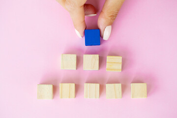 Woman hand putting and stacking blank wooden cubes on desk with copy space for input wording and infographic icon.