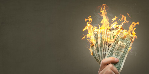 Burning Dollar banknotes held by a hand