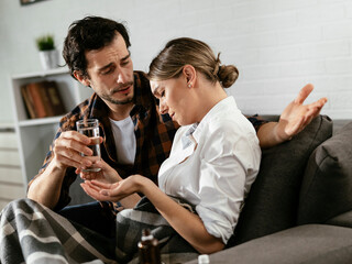 Young woman sick in bed. .Woman drinking medicine, having stomach pain. Husband comforts his wife.