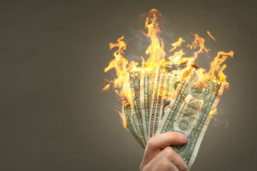 Burning Dollar banknotes held by a hand