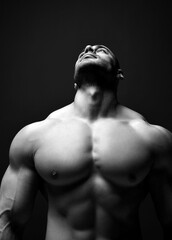 Obraz na płótnie Canvas Naked pumped up upper body with biceps of handsome brutal man athlete standing looking up showing perfect fit over dark background. Sport men body concept