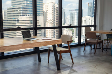 Fototapeta premium Nobody modern office with laptop, clipboard on wooden desk and chair in busuness district