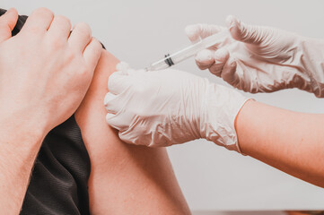 Vaccination close up, injection of vaccine in hand, doctor in white gloves.