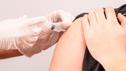 Vaccination close up, injection of vaccine in hand, doctor in white gloves.