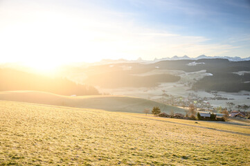 sunrise over the hills of Emmental with Bernese Alps in the distance and overlooking the village of Zäziwil
