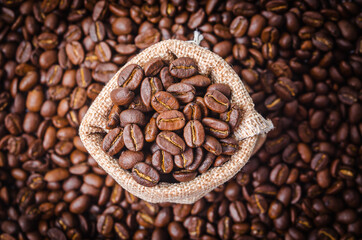 Coffee beans in sack bag on coffee beans background.