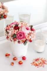 Bouquet with roses, peony and spikelets in pink colors. Stabilized flowers in a white vase at home on the dressing table. Interior decor.