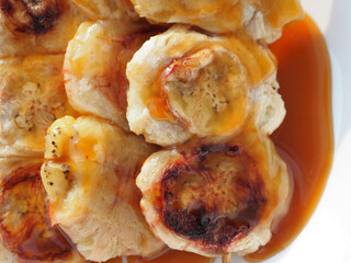 Grilled banana with fragrant caramel sauce from Thailand on white background.