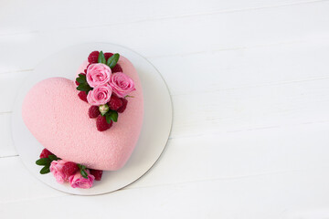 Modern  mousse cake .Heart shape  cake  decoraited of pink roses and raspberries .White wooden board.Concept for Wedding , St. Valentine's Day, Mother's Day, Birthday Cake.