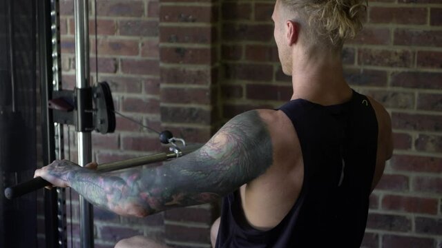 Tattoo man muscles in home gym doing lat rows