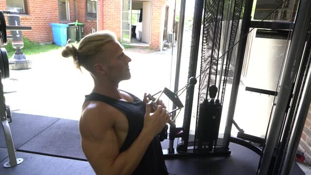 Tattoo man muscles in home gym doing incline cable lat row
