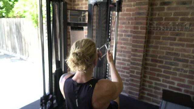 Tattoo man muscles in home gym doing cable lat rows rowing