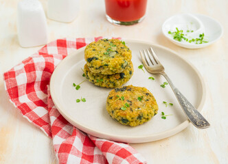 Fried burgers or cutlets of bulgur, carrots and spinach on a light ceramic plate on a light concrete background. Bulgur recipes.
