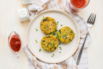 Fried burgers or cutlets of bulgur, carrots and spinach on a light ceramic plate on a light concrete background. Bulgur recipes.