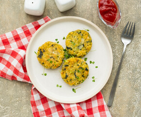 Fried burgers or cutlets of bulgur, carrots and spinach on a light ceramic plate on a gray concrete background. Bulgur recipes.