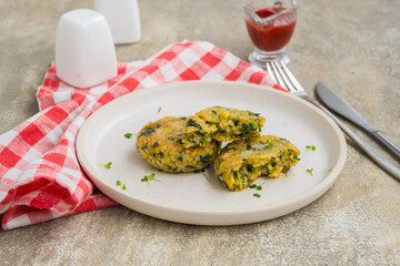 Fried burgers or cutlets of bulgur, carrots and spinach on a light ceramic plate on a gray concrete background. Bulgur recipes.