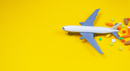 model airplane with multicolored pills from motion sickness close-up on a yellow background. concept illness in travel.selective focus - obrazy, fototapety, plakaty