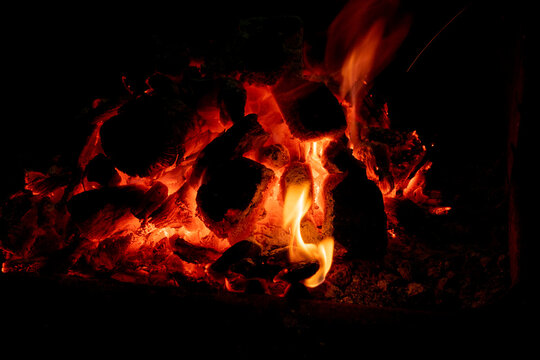 Incandescent charcoal ember in orange and yellow tones