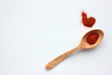 Red paprika specie in wooden spoon on white background. Top view, copy space
