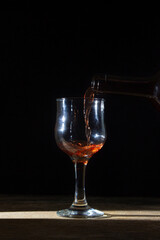 Homemade red wine is poured into a glass on a dark background. Glass of red wine on a black background. Alcoholic beverage
