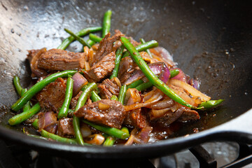 Tri-tip steak, green beans strings, onions in a cast iron cooking wok. Sautéed in organic oysters sauce.