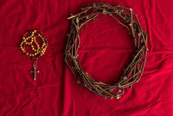 Crown of thorns and Rosary beads on red background.