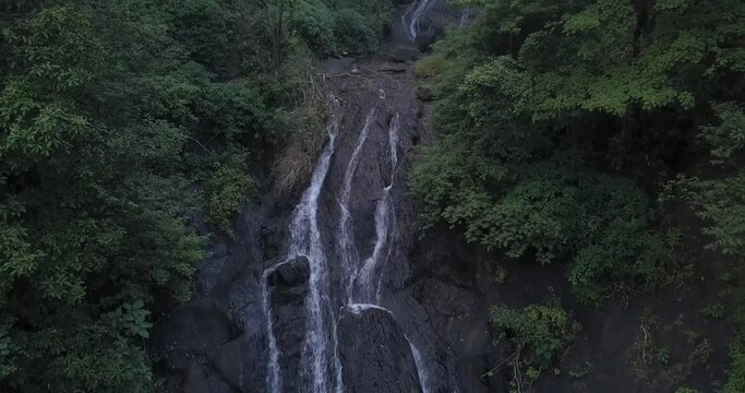 Waterfall Flowing Down On Rocky Mountain Slope Between Dense Foliage In Tropical Forest Of Cotigao Wildlife Sanctuary, South Goa, India. - Zoom In