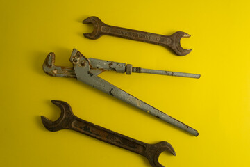 The old rusty  wrench on the yellow background with traces of dirt