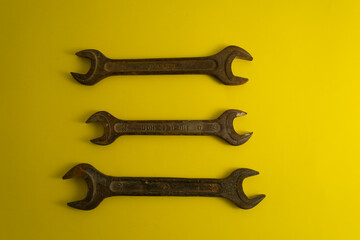 The old rusty  wrench on the yellow background with traces of dirt