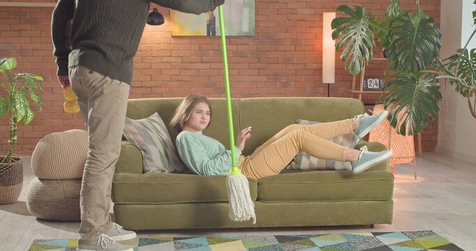 Lazy teenage girl listens to music, father asks her to mop the floor, she refuses to do it and leaves room